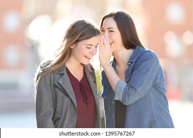 Gossip woman telling secret to her friend in the street