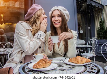 Gossips With Best Friend. Horizontal Shot Of Beautiful Woman Whispering To Her Friend's Ear While Drinking Coffee In French Vintage Cafe. Women Friends Gossiping During Coffee Time. French Style Women