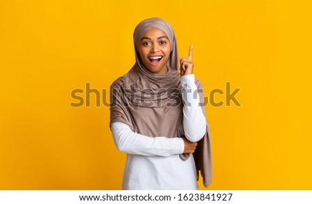 I Got It. Young Afro Woman In Hijab Pointing Finger Up, Having Idea Or Problem Solution, Standing Over Yellow Background