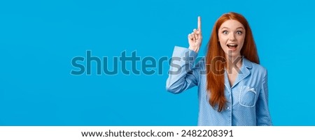 I got solution, hear me out. Attractive excited redhead girl in nightwear sharing her ideas, raising index finger eureka gesture, talking to you, saying plan, standing in pyjamas, blue background.