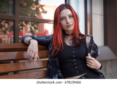 Goth punk beautiful girl with red hair walks in the city