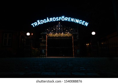 Gothenburg, Sweden - 10 21 2019: A Cast Iron Gate With A Neon Sign Above It And 2 Lamps At The Sides