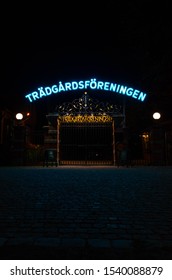 Gothenburg, Sweden - 10 21 2019: A Cast Iron Gate With A Neon Sign Above It And 2 Lamps At The Sides And Blue Reflection In Front Of It