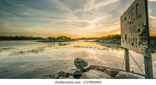 Gothenburg, Sweden - June 17 2014: Sunset In The Archipelago With An Old Worn Sign Warning For Underwater Power Cable.