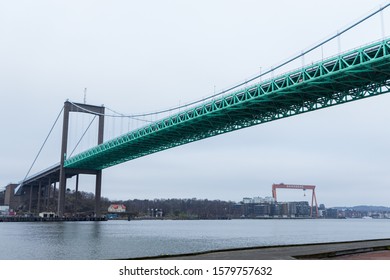 Gothenburg / Sweden - November 23 2019: Panorama of famous bridge "Älvsborgsbron" in Gothenburg with the massive crane "Eriksberg" in the distance in the harbour during a winter day. 