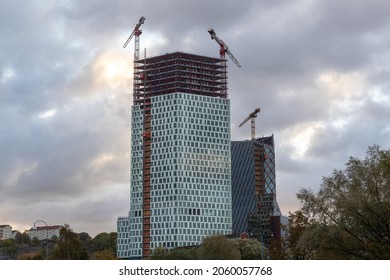 Gothenburg, Sweden - Oct 15 2021: Two high rise buildings under construction with unfinished top floors. Lifting cranes and construction workers visible.