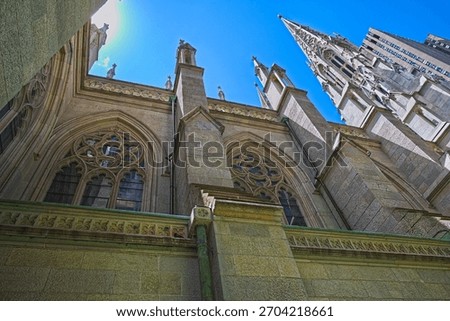 Gothic architectural elements of St. Patrick's Cathedral dominate the scene, showcasing intricate stonework and pointed arches against a clear blue sky. 