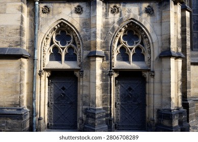 Gothic architecture featuring two ornate arched doorways on a historical building facade, showcasing intricate stonework and iron doors.