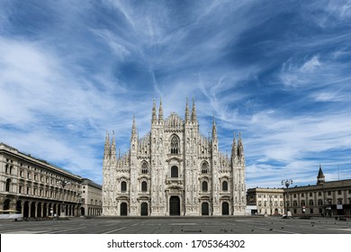 The gothic Duomo Cathedral facade in Milan, Italy on a beautiful spring day. Empty Duomo square. Blue sky with scattered soft clouds. Lockdown, curfew