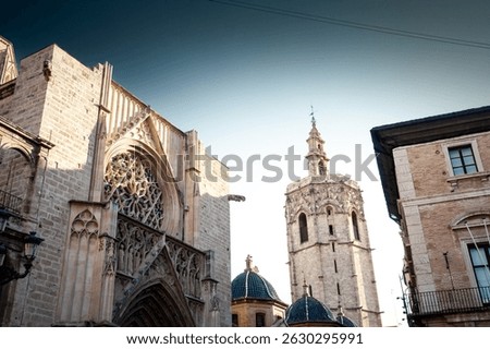 Gothic facade of Valencia Cathedral with ornate rose window rises beside the octagonal Micalet bell tower under evening sky, highlighting historic architecture that shapes the city’s old town skyline.