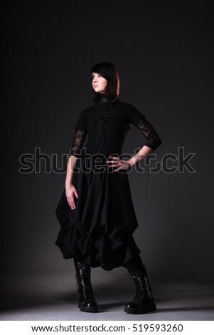 Gothic girl wearing black long dress on dark background


