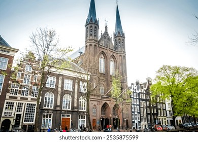 A Gothic Revival church in Amsterdam, Netherlands, dominates the scene. The De Krijtberg boasts a tall spire and grand windows, a testament to its rich history and enduring role as a place of - Powered by Shutterstock