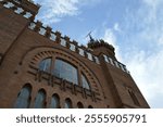 Gothic-style brick façade of Castell dels Tres Dragons in Barcelona, with intricate architectural details and decorative tiles against a vibrant sky