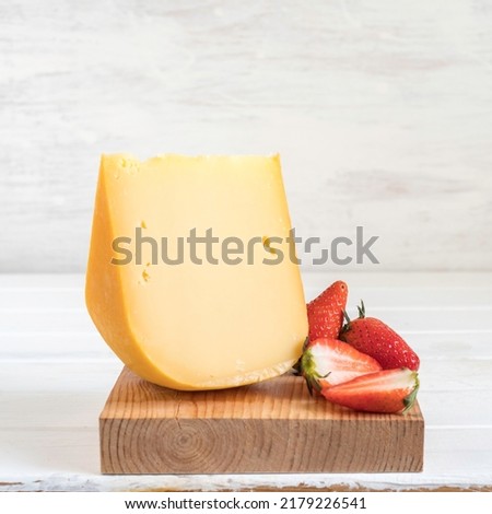 Gouda cheese and fresh strawberries on wooden background.