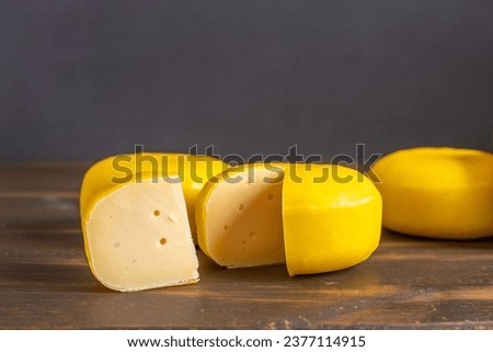 Gouda cheese on dark wooden background.