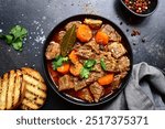 Goulash (meat stew with tomatoes and paprika) - traditional dish of hungarian cuisine on a dark slate, stone or concrete background.Top view with copy space.