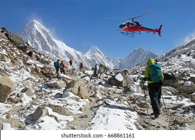 Goup of climbers in the Himalayas, view on peaks Lingtren, Pumori and Khumbutse. Rescue helicopter in action, Nepal