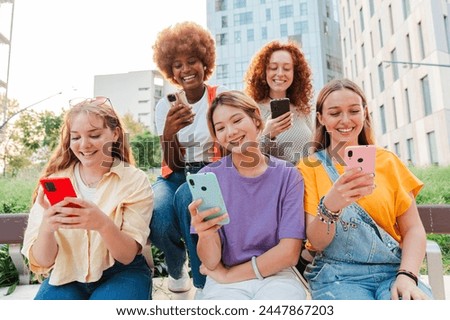 Goup of only women having fun using their cellphones. Females sitting outside and browsing on internet with a smartphone connection app. Girls watching the socialmedia with a mobile phone on a meeting