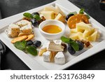 Gourmet Cheese Platter with Honey Dip and Fresh Grapes on White Ceramic Plate - High Contrast Food Photography.