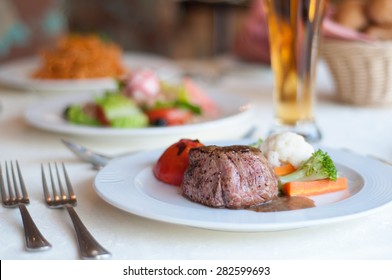 Gourmet cuisine at restaurant. Beefsteak and green vegetables platter on  table.