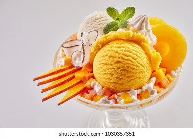 Gourmet dessert with artisanal mango and vanilla Italian ice cream garnished with sliced fresh fruit, white chocolate twirls and pineapple rings with whipped cream - Powered by Shutterstock