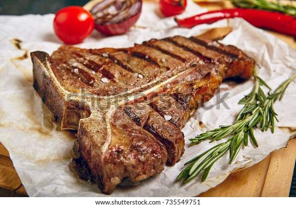 Gourmet Grill Restaurant Steak Menu - T-Bone Beef\
Steak on Wooden Background. Black Angus Prime Beef Steak. Beef\
Steak Dinner
