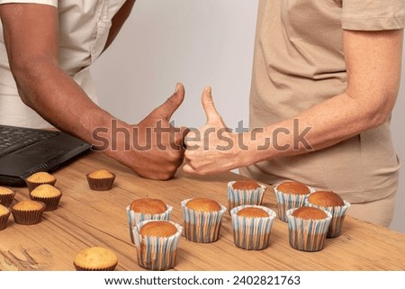 Gourmet Harmony: Mixed Couple Sharing the Joy of Muffins on a Wooden Table with thumb in sign of victory