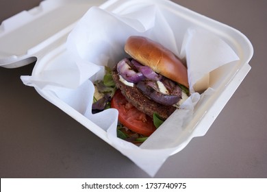 Gourmet Impossible Burger In A Takeout Box Isolated On A Gray Background. Selective Focus On The Plant-based Meat Patty. Healthy And Delicious Vegan Food Concept.