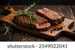 Gourmet prepared Premium steak with rosemary, cut into equal pieces on light ceramic dish in a rustic dark brown style, on an old wooden board. Different spices and rosemary add contrast.