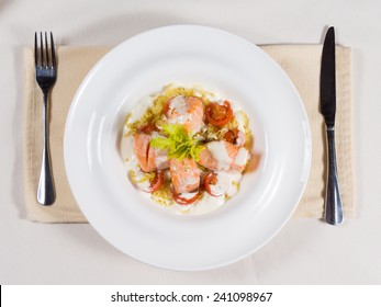 Gourmet Salmon Seafood Starter With Bite Sized Portions Of Fish Drizzled With A Cream Sauce And Seasoned With Herbs, Overhead View On A White Plate