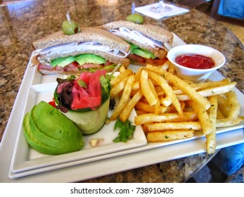 Gourmet Sandwich Turkey Bacon Avocado Club Sliced In Half With French Fries And Ketchup Dip