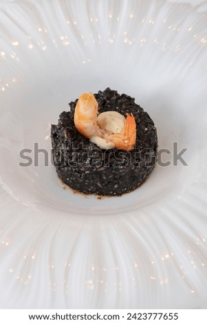 Gourmet seafood dish with black squid ink rice and a succulent shrimp perched atop, culinary experience created with the finest ingredients and a balanced infusion of textures and briny, ocean flavors