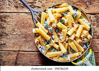 Gourmet Serving Of Italian Ricotta Pasta With Healthy Green Spinach And Pine Nuts Topped With Grated Parmesan Cheese And Served On A Pan, Overhead View On An Old Weathered Wooden Table