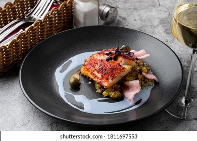 Gourmet Special In A Fancy Restaurant: Fried Cod Fillet With Couscous And Blue Sauce On A Wide Black Plate