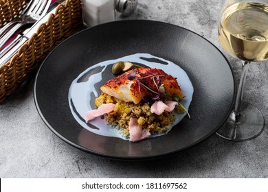 Gourmet Special In A Fancy Restaurant: Fried Cod Fillet With Couscous And Blue Sauce On A Wide Black Plate