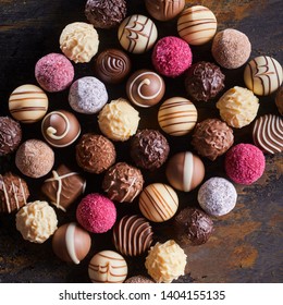 Gourmet speciality chocolate bonbons or pralines arranged in a neat rectangle on rustic wood table viewed top down