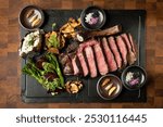 A gourmet spread features juicy steak slices, grilled veggies, mushrooms, and condiments on a dark platter, exuding a rustic, elegant vibe.