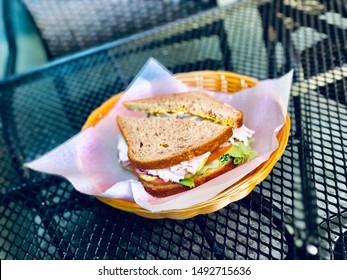 Gourmet Turkey Sandwich On Rye Whole Wheat Bread With Deli Meat Lettuce Tomato Avocado In Food Basket Healthy Eating On Table Outside
