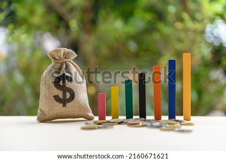 Government budget, public spending concept : Dollar bag, increasing height bar graphs on a table, depicts the increment in annual financial budget or revenues that government collects from tax payer.