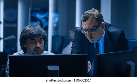 Government Chief Of Cyber Security Consults Operations Officer Who Works On Computer. Specialists Working On Computers In System Control Room.