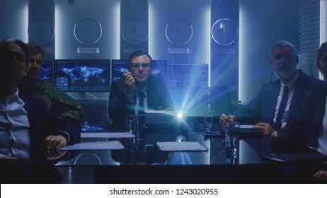 Government Officials, Military Men And Business Executives Watching Presentation In The Conference Room. Working Projector On The Table. Collaboration Of Important People.