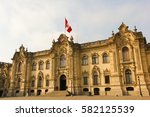 Government Palace of Peru in Lima before sunset with two guardians by the main entrance and the red and white flag on top of the building. Baroque Revival architecture popular building