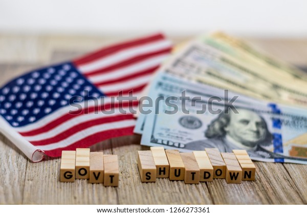 Government Shutdown USA\
concept with American flag and money bills on white background and\
wooden board