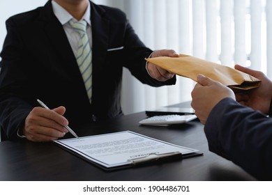 Government tax officials are accepting citizens of bribes wrapped in brown envelopes. To open the way for annual tax evasion, the concept of bribery officials to avoid taxes. - Shutterstock ID 1904486701