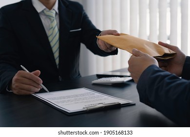 Government tax officials are accepting citizens of bribes wrapped in brown envelopes. To open the way for annual tax evasion, the concept of bribery officials to avoid taxes. - Shutterstock ID 1905168133