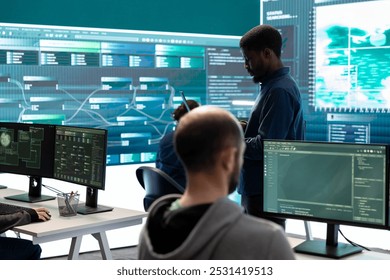 Governmental hackers breaching network security with advanced techniques, cyber defense in action. Team of IT experts working on gaining access to collect information, big screen. - Powered by Shutterstock