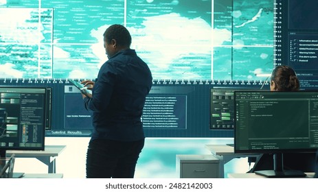 Governmental hackers exploiting network systems in high tech office, executing cyber operations for national server security. Focus on data protection and online safety to combat cybercrime. Camera A.