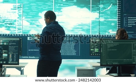 Governmental hackers exploiting network systems in high tech office, executing cyber operations for national server security. Focus on data protection and online safety to combat cybercrime. Camera A.