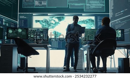 Governmental hackers performing a cyber attack simulation after studying the national database servers. Experts working on IT security, data breach prevention against ransomware. Camera B.