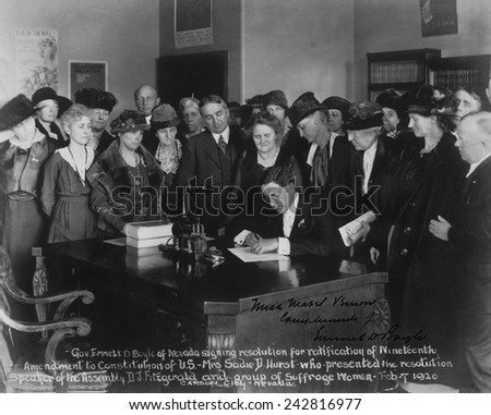 Governor Emmett D. Boyle of Nevada signing resolution for ratification of Nineteenth Amendment to Constitution of U.S. as a group of suffragists watch.